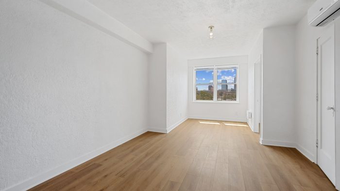 an empty room with hardwood floors and a window at The St Regis Apartments