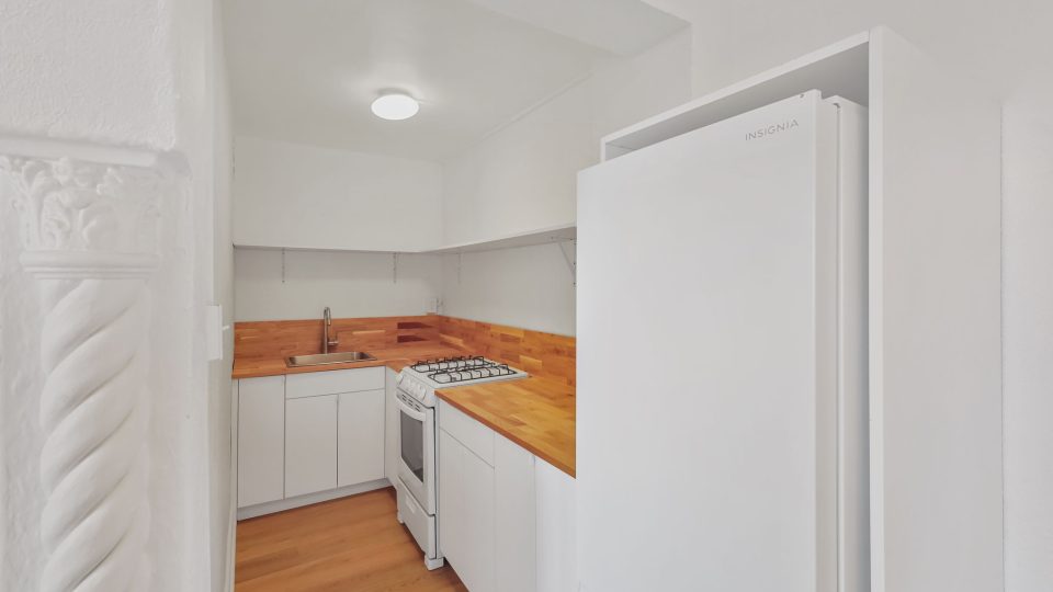 a small kitchen with a refrigerator and stove at The St Regis Apartments