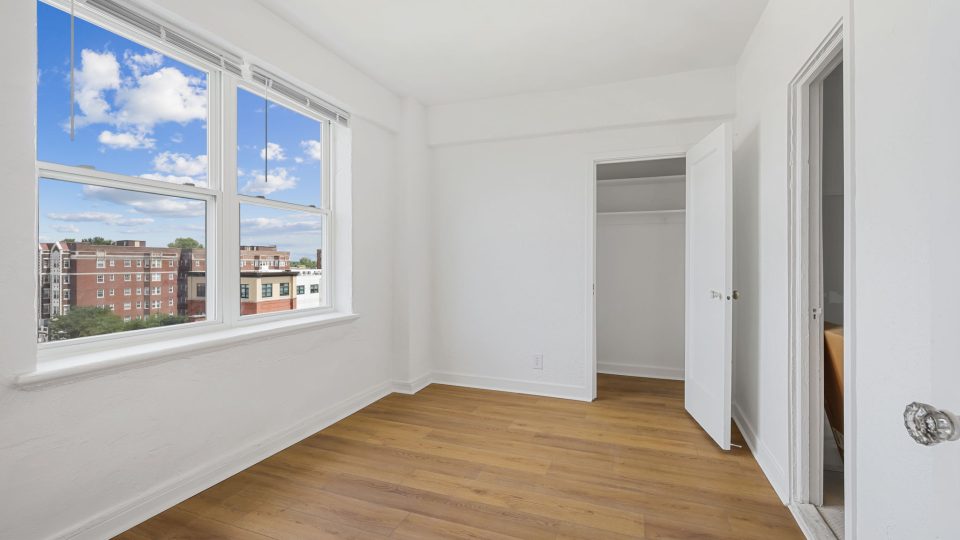 a white empty room with hardwood floors and windows at The St Regis Apartments