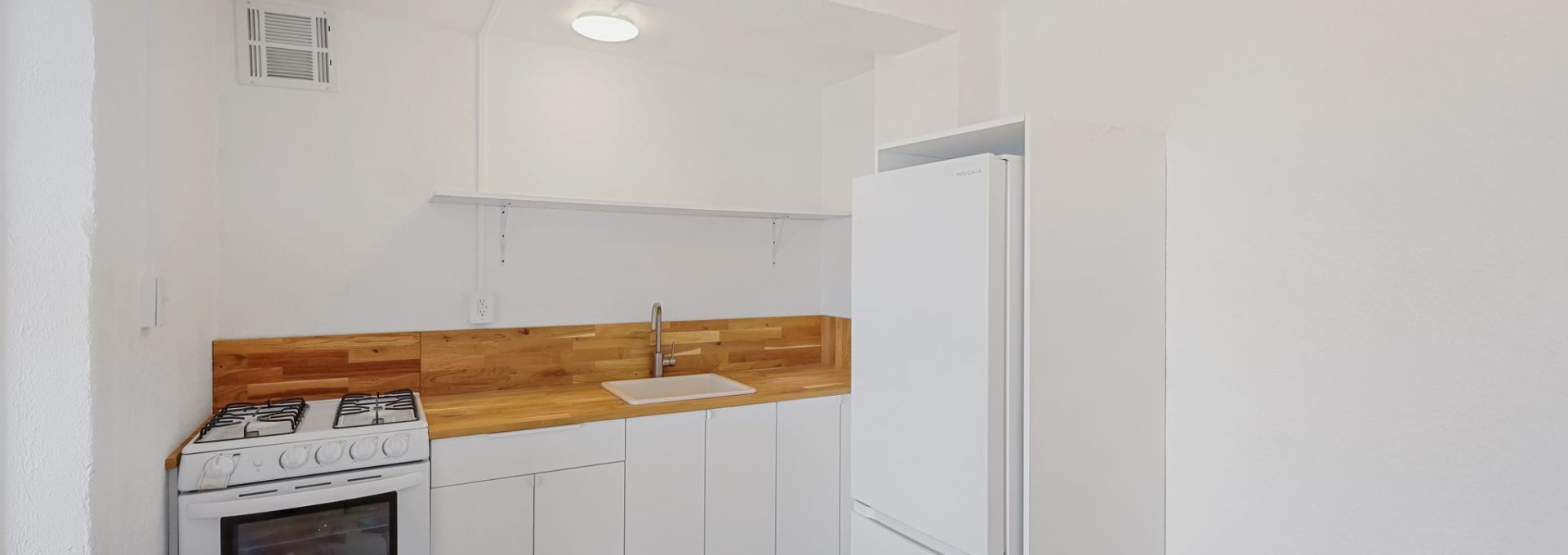 a white kitchen with a stove and refrigerator at The St Regis Apartments