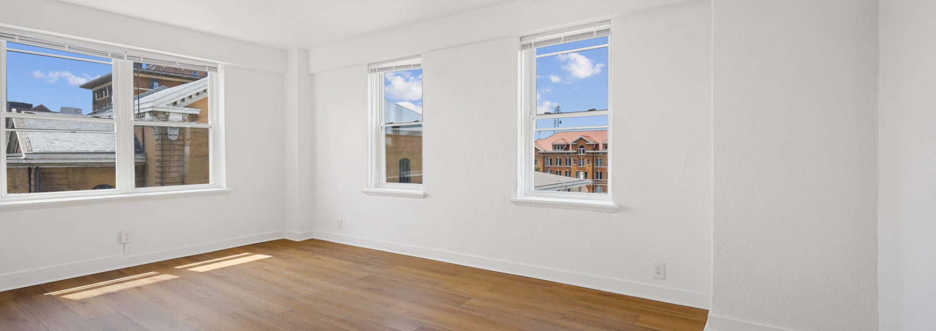 a empty room with hardwood floors and windows at The St Regis Apartments