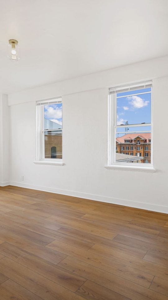 a empty room with hardwood floors and windows at The St Regis Apartments