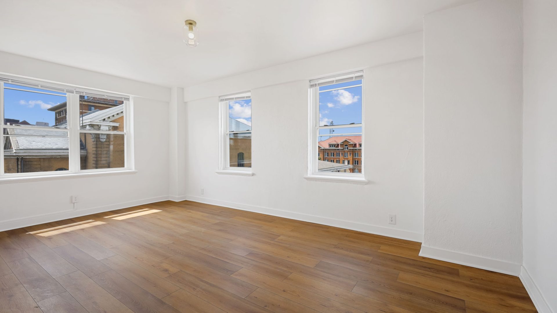 a empty room with hardwood floors and windows at The St Regis Apartments