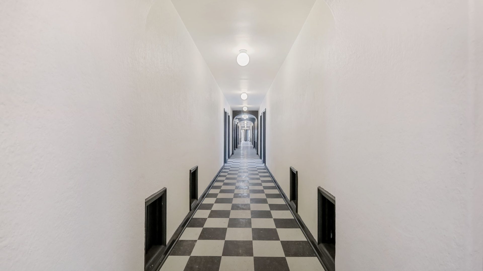 a hallway with a checkered floor and a white ceiling at The St Regis Apartments