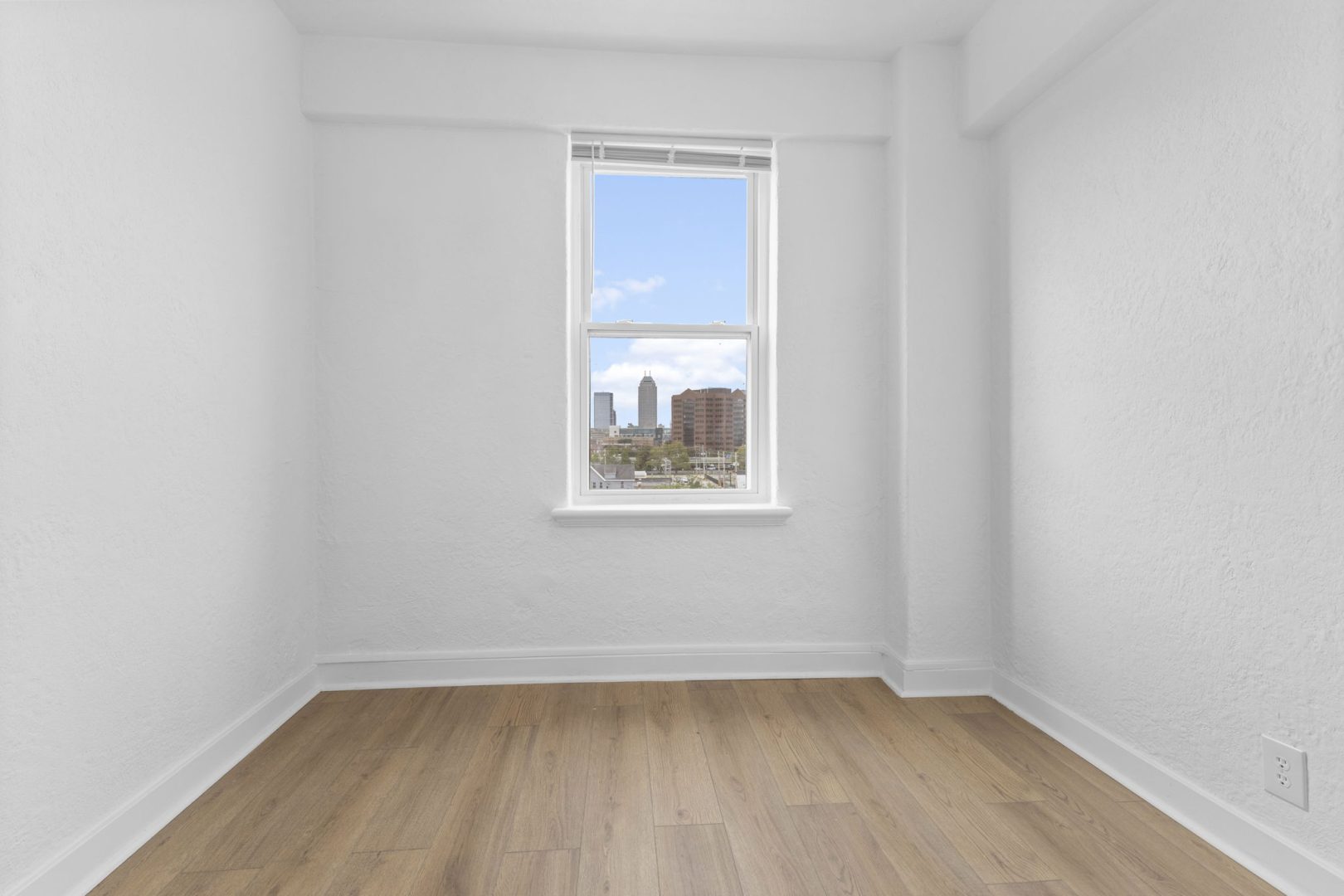 a empty room with hardwood floors and a window at The St Regis Apartments