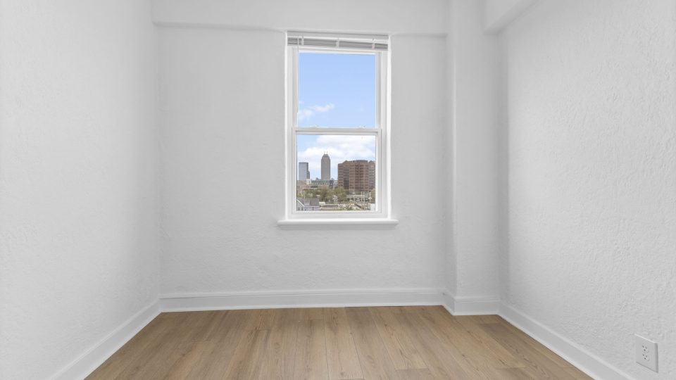 a empty room with hardwood floors and a window at The St Regis Apartments