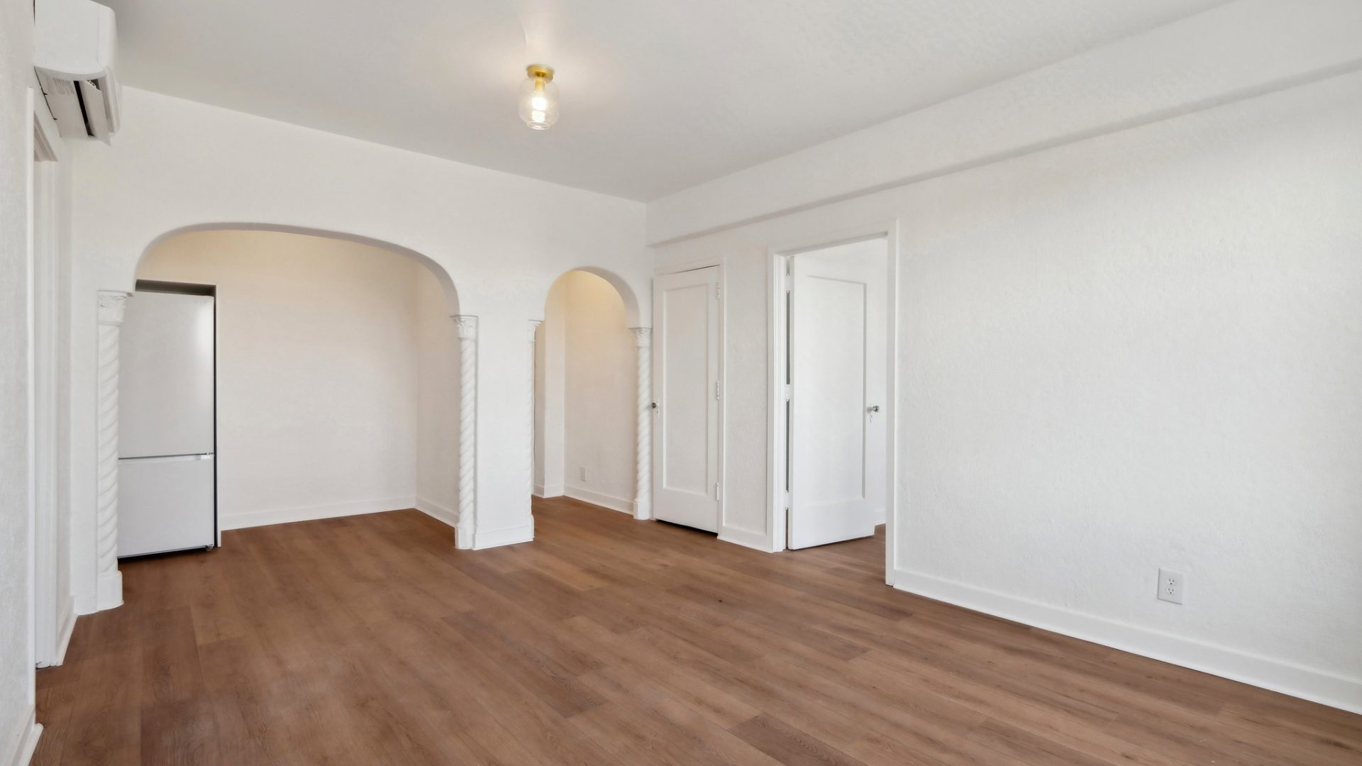 an empty room with hardwood floors and white walls at The St Regis Apartments