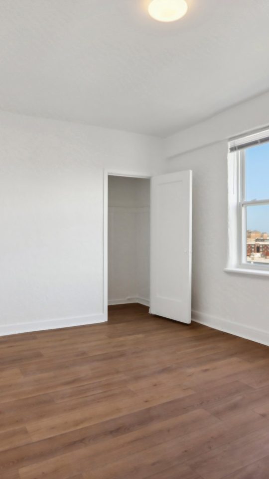 an empty room with hardwood floors and a window at The St Regis Apartments