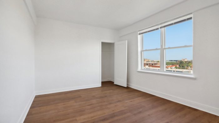 an empty room with hardwood floors and a window at The St Regis Apartments