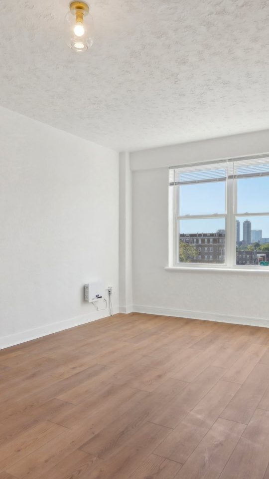 an empty room with hardwood floors and a window at The St Regis Apartments